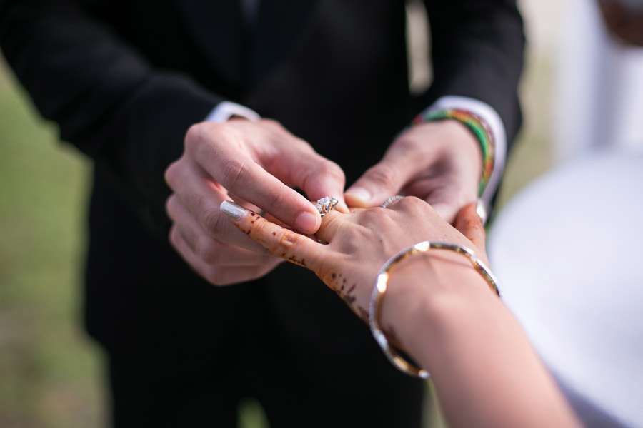 A couple joyfully puts on wedding rings, marking their special moment in a wedding in Thailand.